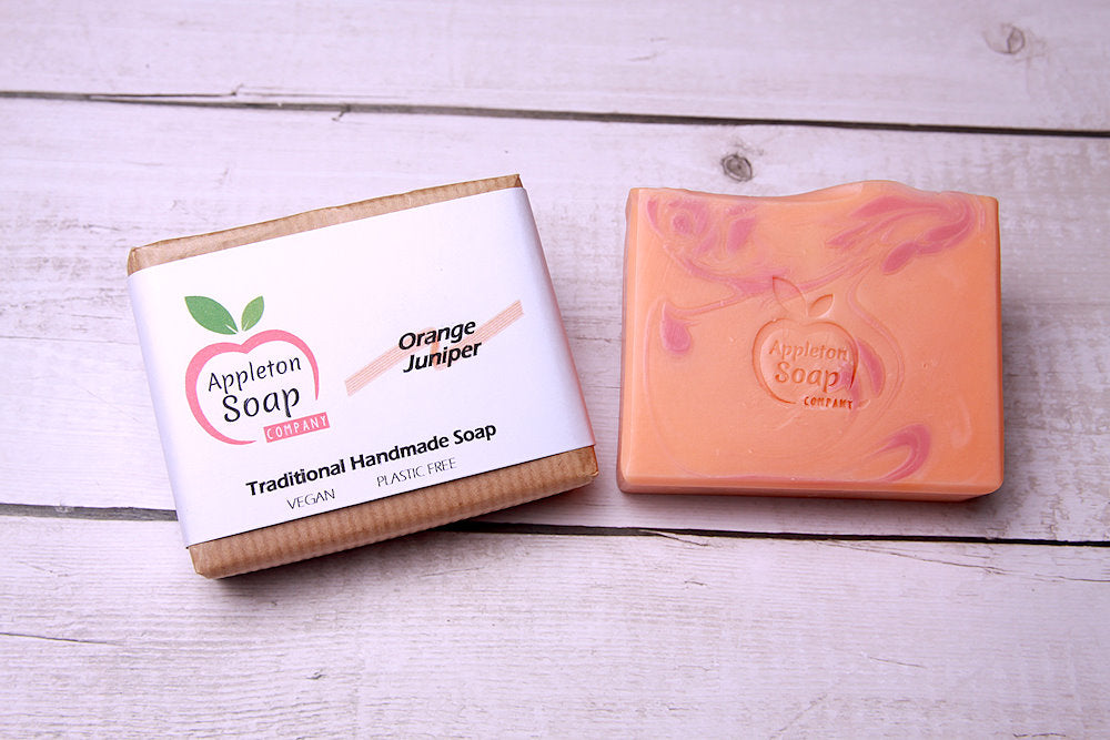Orange juniper soap bar next to wrapped bar