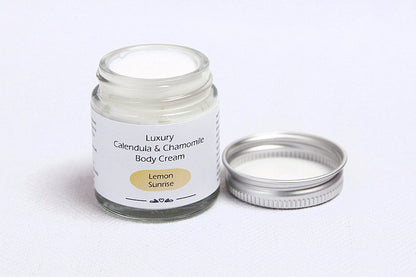 Open glass jar with metal lid with Lemon sunrise luxury body cream
