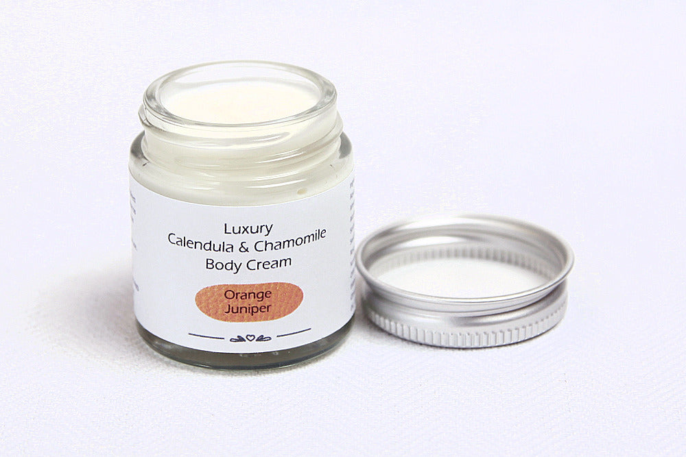 Luxury Orange Juniper Body cream in open glass jar with metal lid